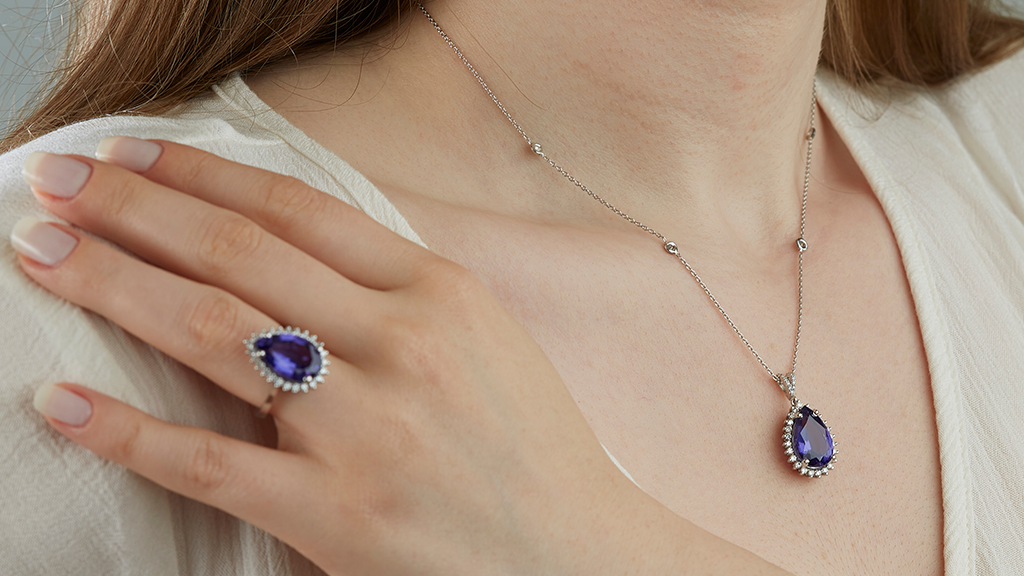 Matching pear-cut purple tanzanite jewelry set with a diamond halo pendant necklace and teardrop gemstone ring.